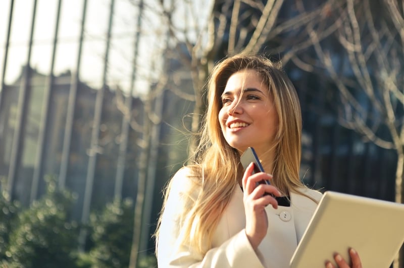 Frau lächelt mit Smartphone: Trendmonitor 2018 zu Videos und Blended Learning